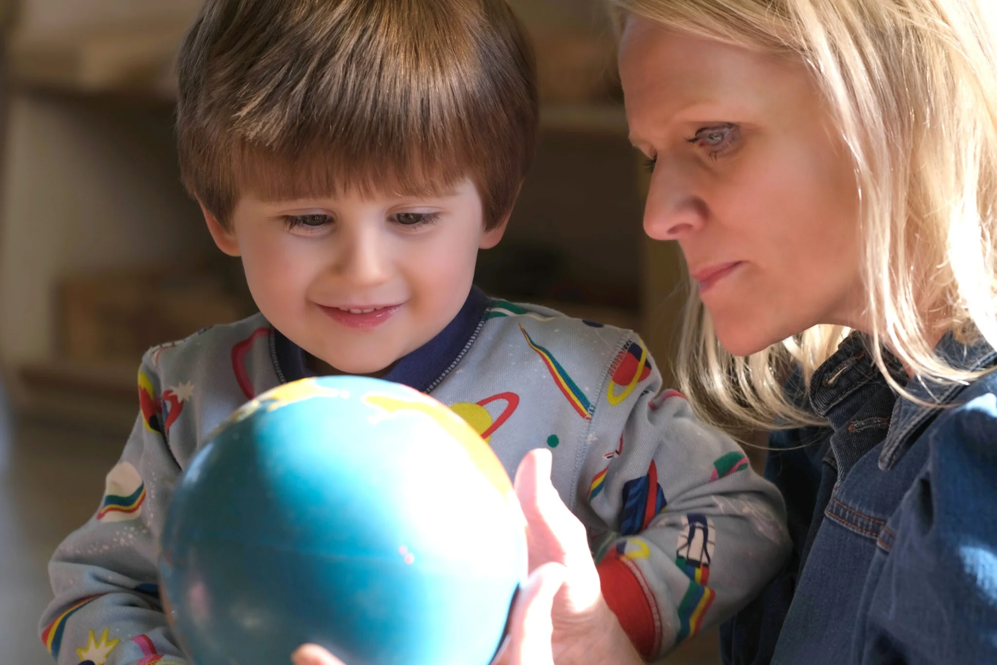 A child and an adult explore a globe together